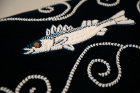 Detail of a fish from Karen Ann Hoffman's (b. 1957, Oneida Nation of Wisconsin) Treaty Rights Footstool, 2014. The beadwork includes a taxidermy fish eye.