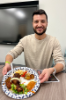 Second-year medical student Adam Greenstein proudly displays the food on his plate, including jollof rice, chicken tikka masala, mac and cheese, and Ghanaian roasted chicken. 