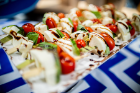 Complimentary hors d’oeuvres, such as these caprese skewers, are served.