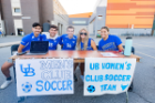 Members of the men's and women's club soccer team pose for a photo at their Campus Fest table. 