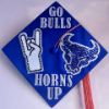 "My grad cap will get everyone in True Blue UB Spirit. I first cut out paper in the shape of the UB Bull logo and the hand symbolizing horns up! Then, I bedazzled the bull and hand using rhinestone stickers. I glued these onto the cap and then attached stickers saying GO BULLS! and HORNS UP!" - Kelsey Kaufman, UB True Blue, First Place 