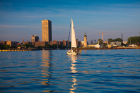 A sailboat sits on a calm Lake Erie with the city behind it. 
