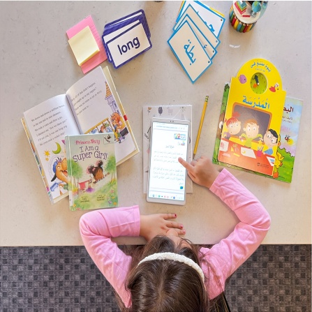 Young child at a table studying in two different languages. 