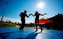 Two people dancing outside under a bright sun. 