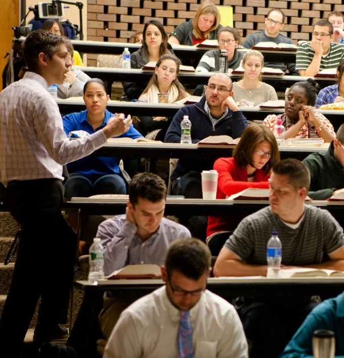 Photo of an instructor talking to students sitting in a classroom. 