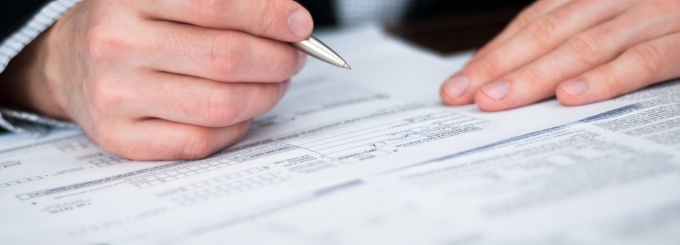 hands signing a document. 