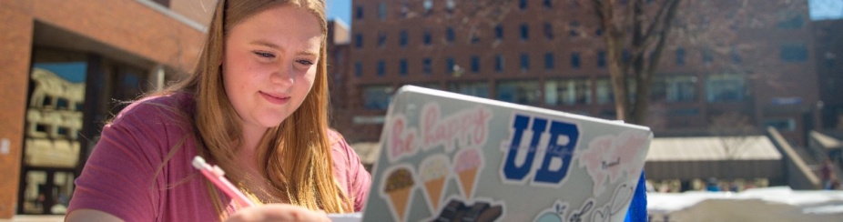 Student working on laptop outside on UB's north campus. 