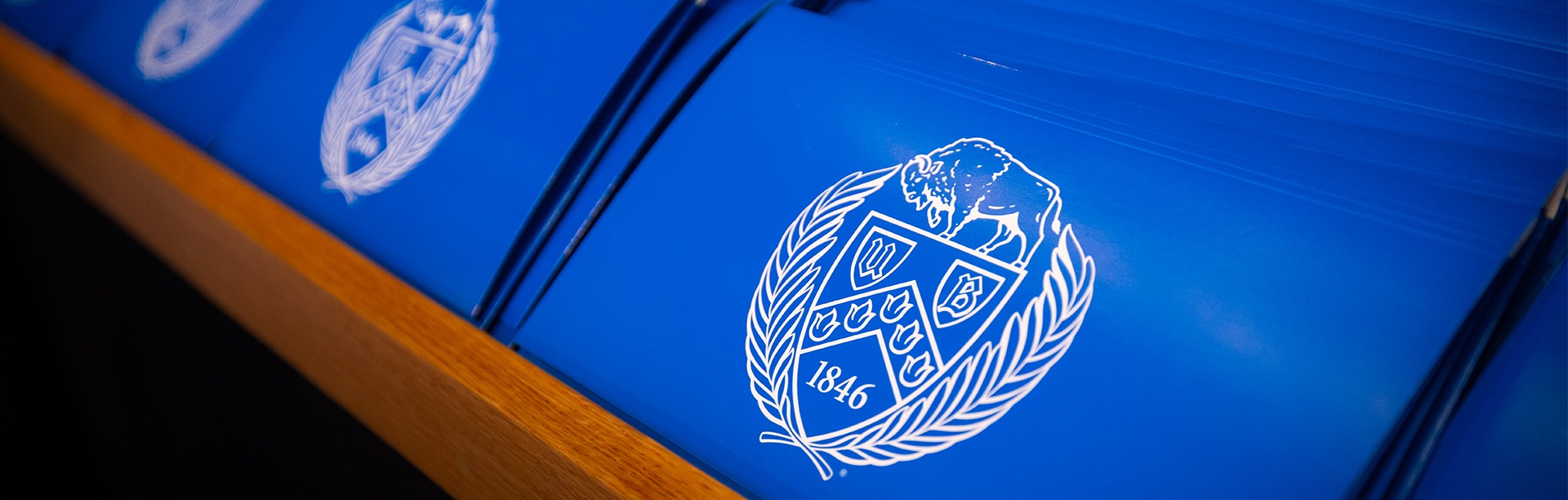 Blue folders with the UB Crest at a University at Buffalo graduation ceremony. 