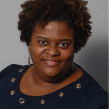 Letitia Thomas poses against a grey background. 