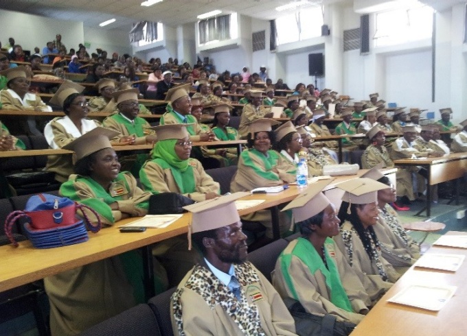 Traditional Healers, wearing graduation caps and gowns, and their families pictured in a lecture hall setting. 