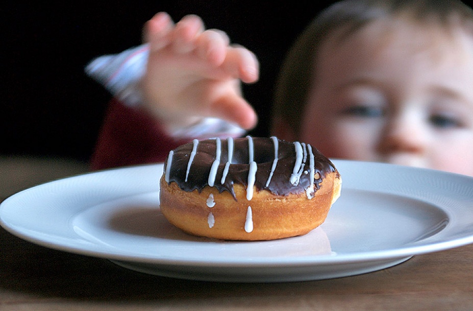 Young child reaching for a donut. 