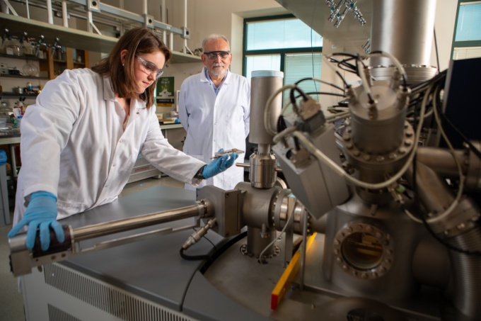Zoom image: University at Buffalo PhD candidate Kaitlin Ordiway (left) prepares to run a sample in a secondary ion mass spectrometer (SIMS). The SIMS can detect targeted compounds in chemical samples extracted from soil. UB chemistry professor Joseph Gardella (right) is leading the Tonawanda Coke Soil Study. Credit: Douglas Levere / University at Buffalo 