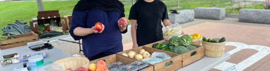 Two students displaying fresh produce at the UB Veggie Van mobile market. 