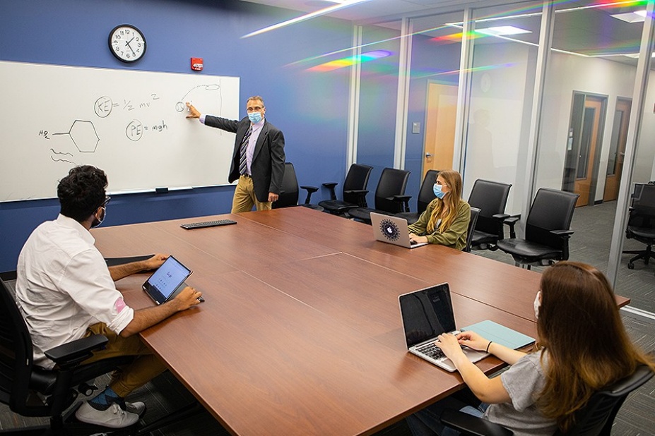 Zoom image: A faculty member teaches in a classroom reconfigured to promote physical distancing. Photo: Douglas Levere 