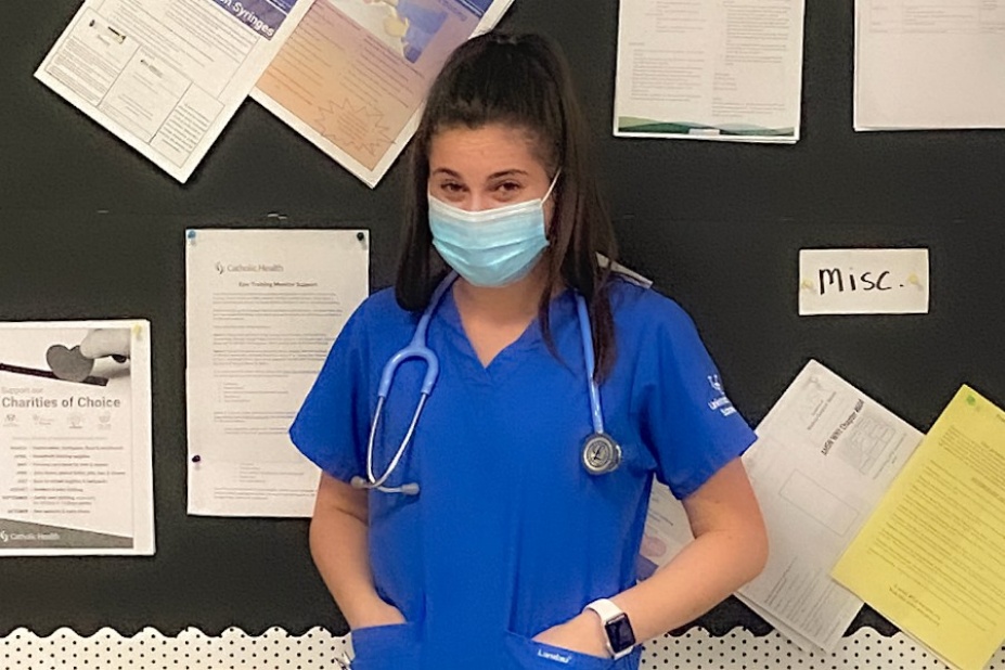 Cara Wojtach pictured wearing scrubs and a face mask with a stethoscope around her neck. 