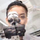 Asian women looking through a microscope. 