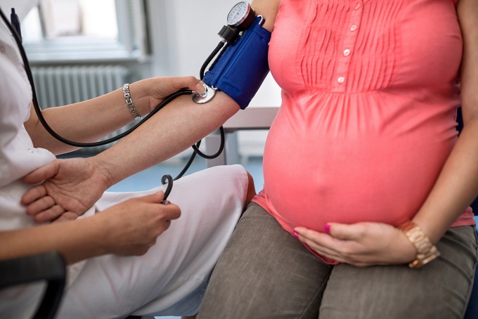A nurse taking blood pressure measurement of a pregnant woman. 
