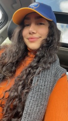 Headshot of Pantea Javidi wearing a blue Sabres baseball cap, orange shirt, and grey knit scarf.