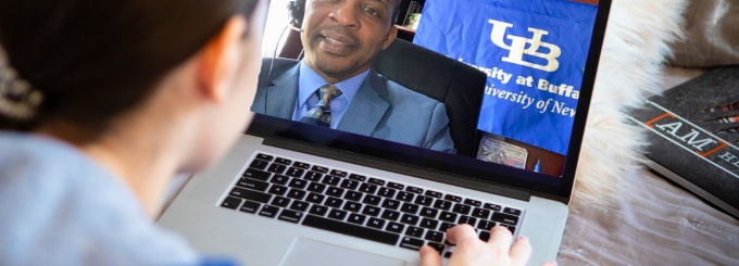A student engages with a UB staff member remotely via a laptop. 