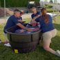 Image of athletic trainers assisting an individual with heat stroke by using an ice bath. 