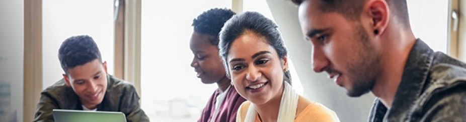 Students around a table looking at a laptop.