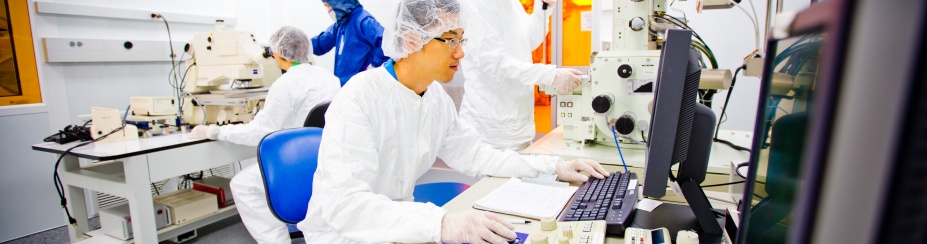 Students working in a lab wearing scrubs and gloves. 