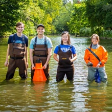 Four student standing in a creek. 