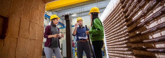Professor Negar Elhami Khorasani, with the Department of Civil, Structural and Environmental Engineering, works with students near a high temperature furnace in Ketter Hall. They are researching how elevated temperatures affect the mechanical properties of steel, concrete and other cementitious materials. Photographer: Douglas Levere. 
