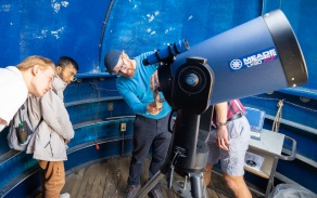 Department of physics instructor with students on the roof of Fronczak Hall using UB's telescope. 