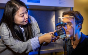 Researcher testing audiology equipment with a volunteer. 