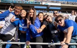 Group of students cheering in stands of football stadium. 
