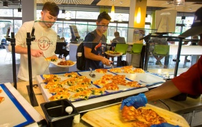 Students at dining hall serving themselves pizza. 