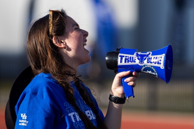 A UB student cheers into a megaphone during a football game. 