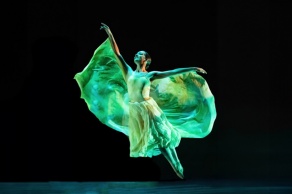 A graceful dancer from the Zodiaque company in mid-leap, lit with green light. 
