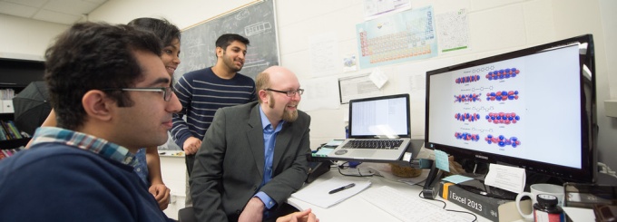 Students in professor Hachmann's lab looking at data on a computer screen. 