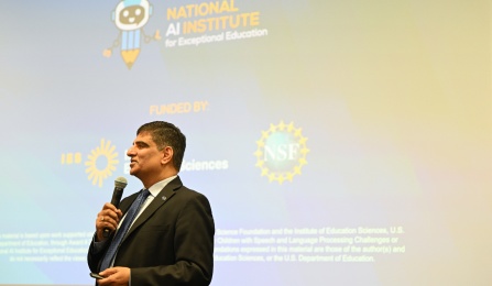 Venu Govindaraju speaking in front of a projector which reads "National AI Institute for Exceptional Education". 