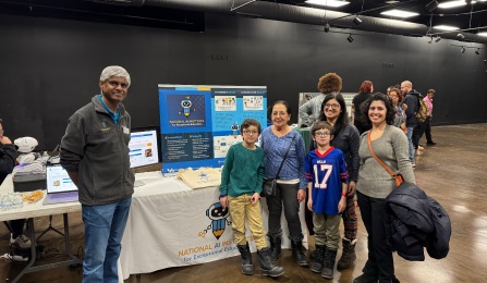 Faculty member poses at table with children and parents. 