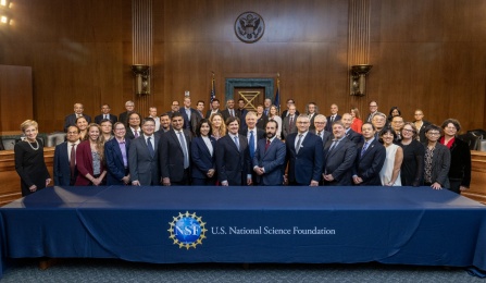 NSF Institute members and government leaders standing behind a table draped with the NSF logo. 