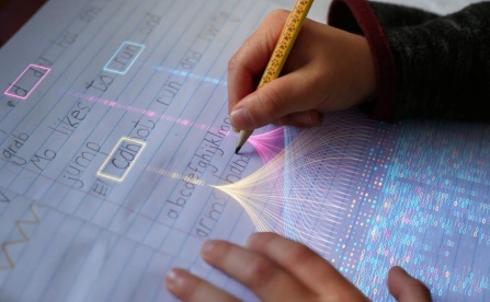 Image of hands writing and computer lighting highlighting connections. 