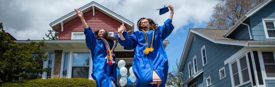 Two UB grads jumping with joy in their commencement gowns. 