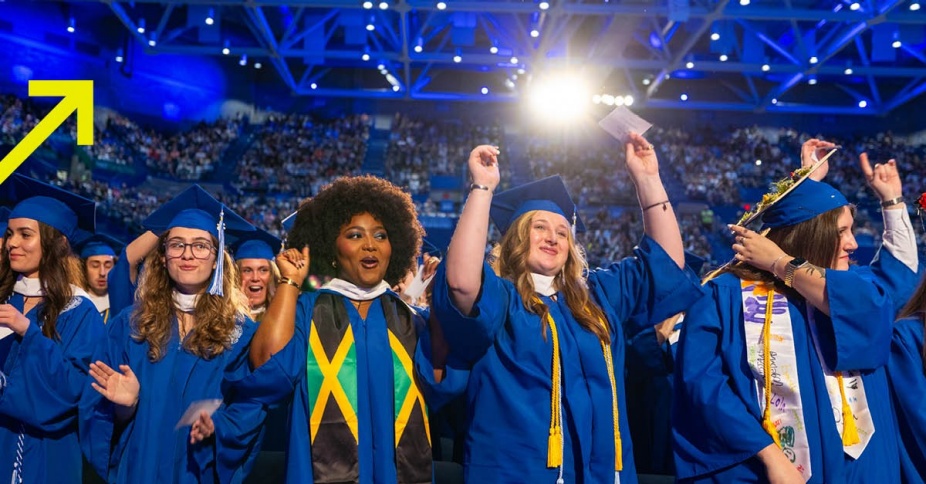 A row of UB students at graduation in blue caps and gowns. 