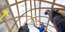 Zoom image: Group of UB students and professors assessing a newly built structure. 