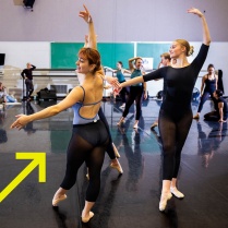 Zoom image: Two UB students in a dance studio warming up for ballet class 