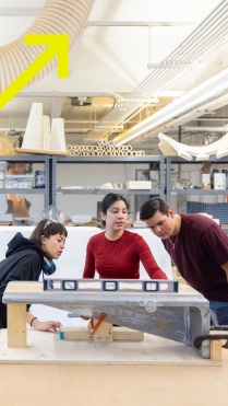 Zoom image: Three UB students leveling a board in a lab 
