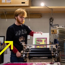 Zoom image: UB student putting ink on a linocut design. 