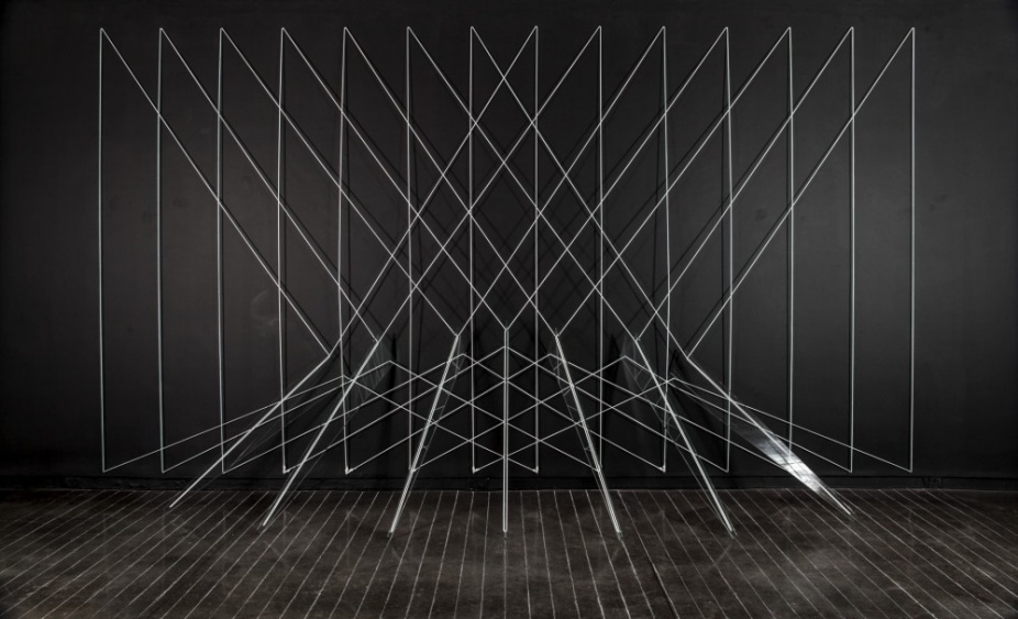 Installation by Lydia Okumura of glass on the ground stretching out white lines towards the wall forming triangular forms overlapping. 