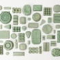 A birds eye photograph of many ceramic objects, all the same shape as plastic containers and glazed in green. 