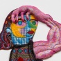 a textile wall work by Maria Guzman Capron. The bust of a figure, made of lightly stuffed fabric and paint, looks out towards the viewer, her hand on her head. 