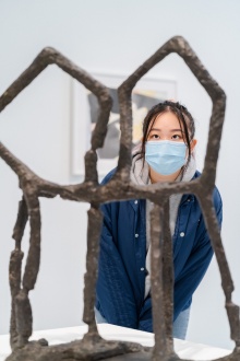 Student looking through a sculpture. 