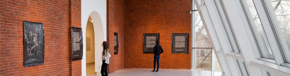 Two students look at an exhibition inside UB Anderson Gallery's atrium. 